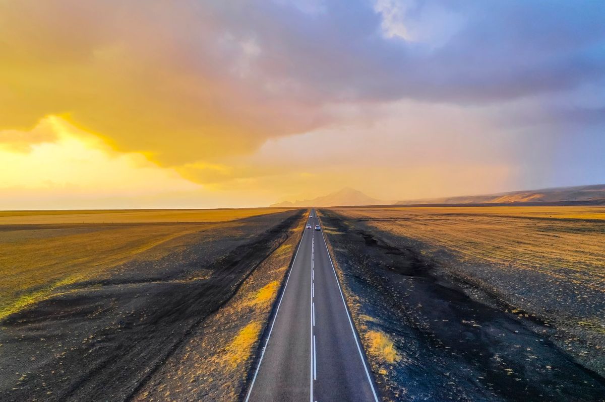 An empty road running toward a golden dawn sky