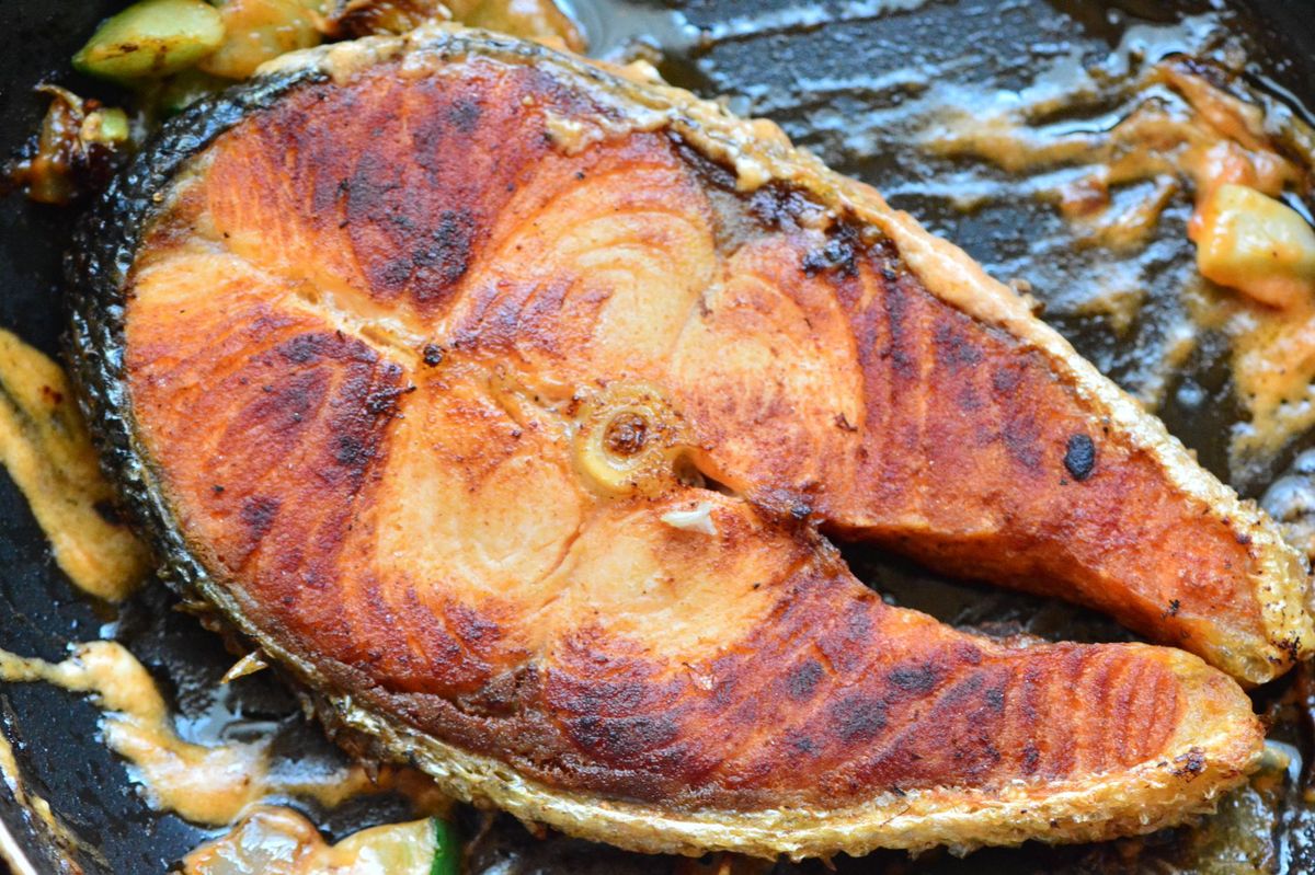 Pan-fried fish sizzling in a cast-iron pan