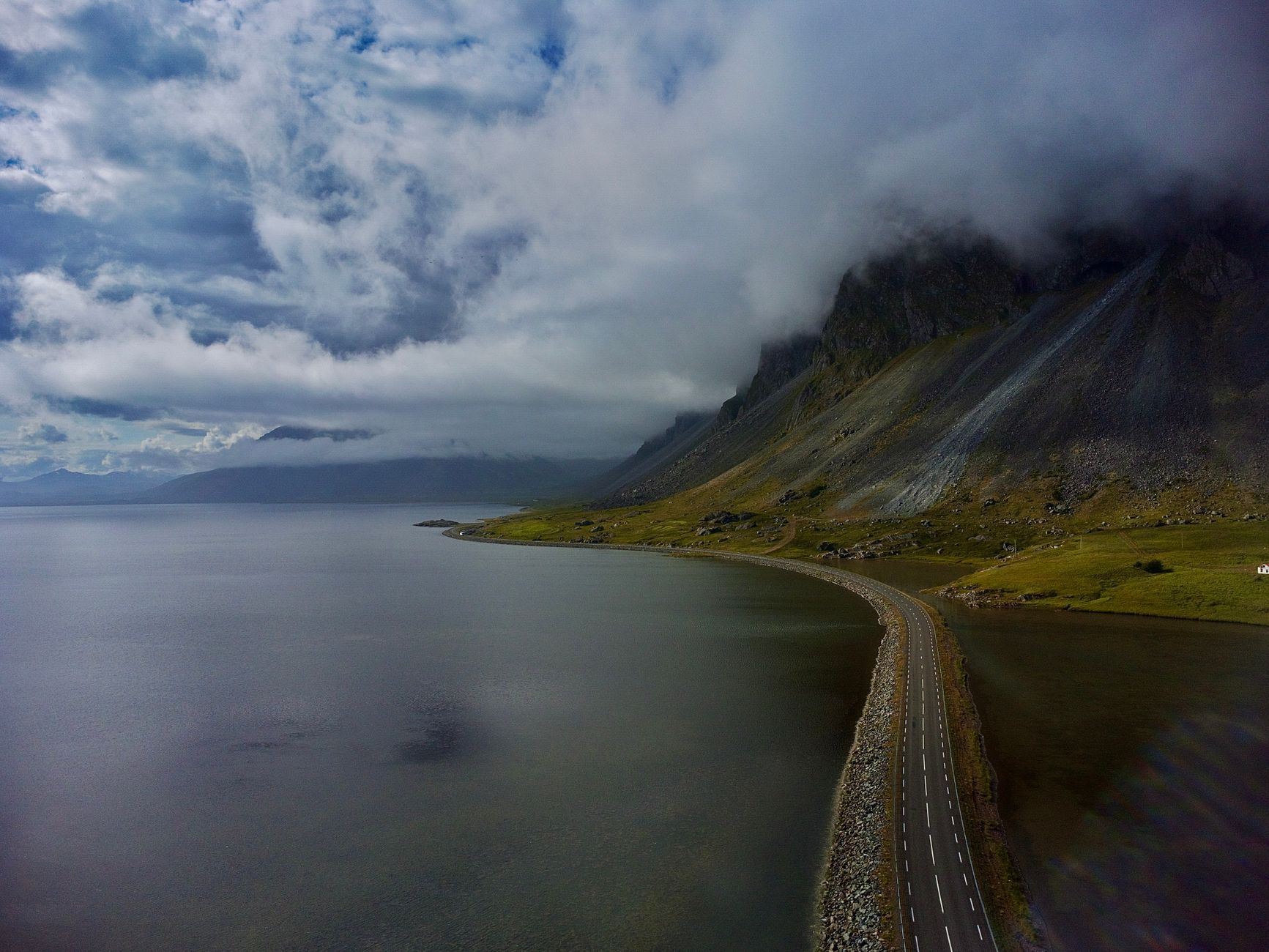 A winding coastal road in Iceland beneath dark mountains