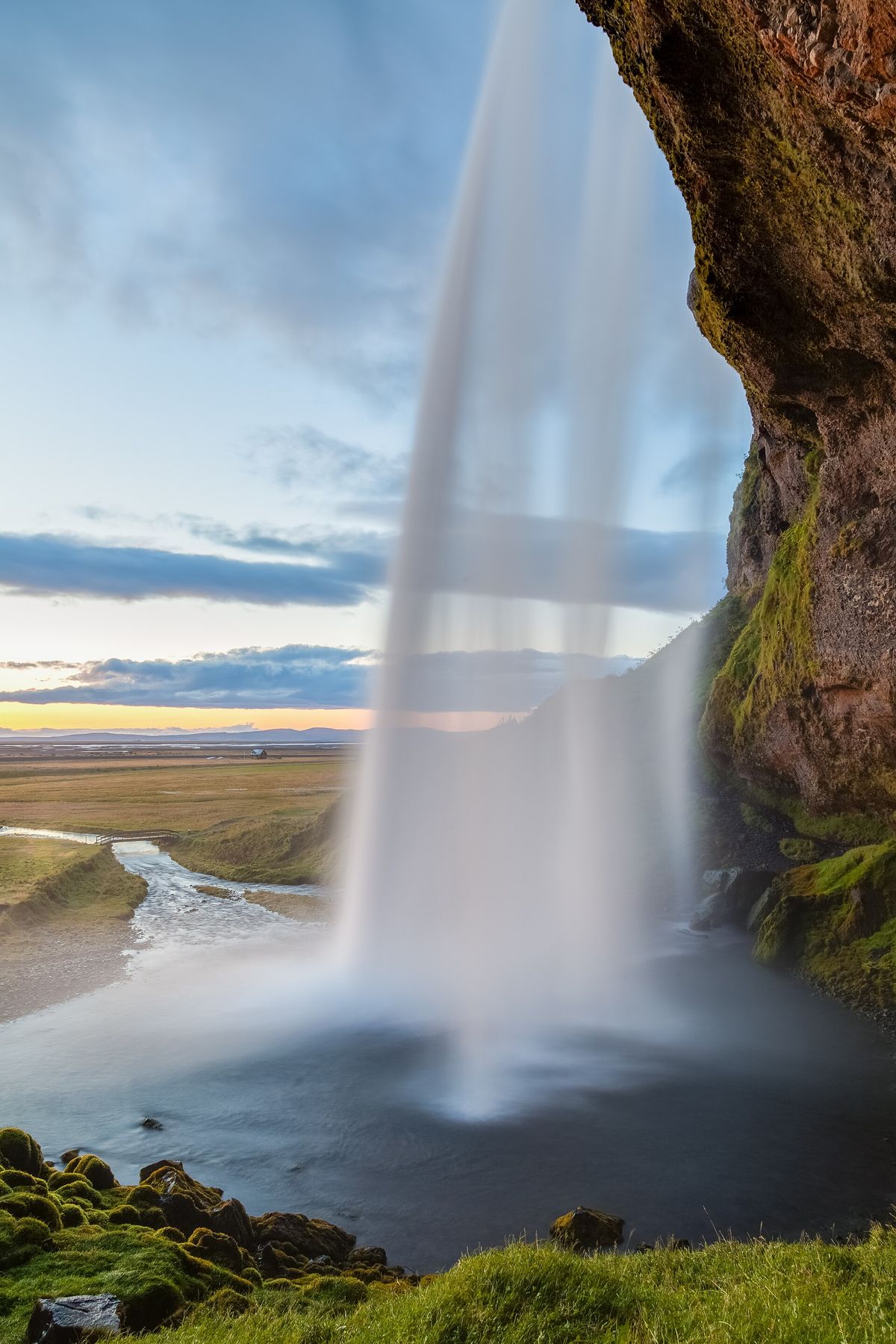 Seljalandsfoss pouring off its old sea cliff at golden hour
