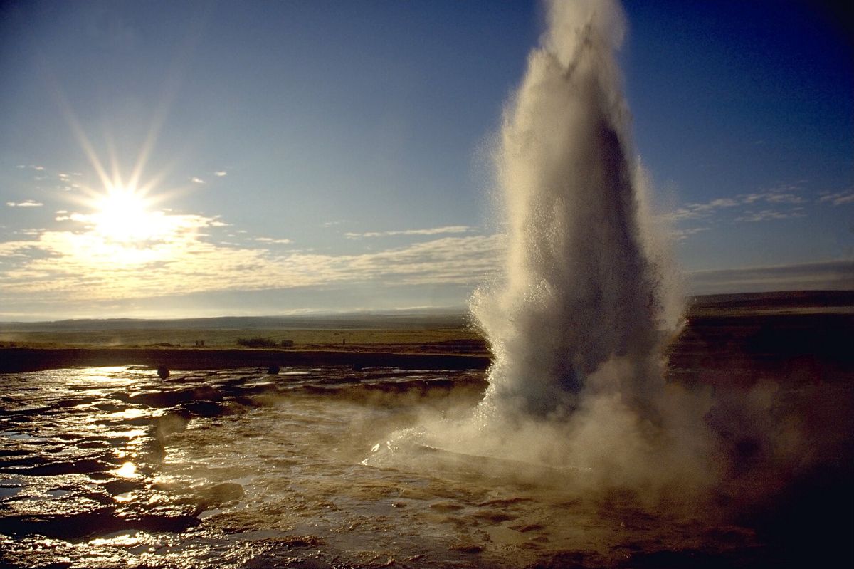 Strokkur erupting against a low golden sun