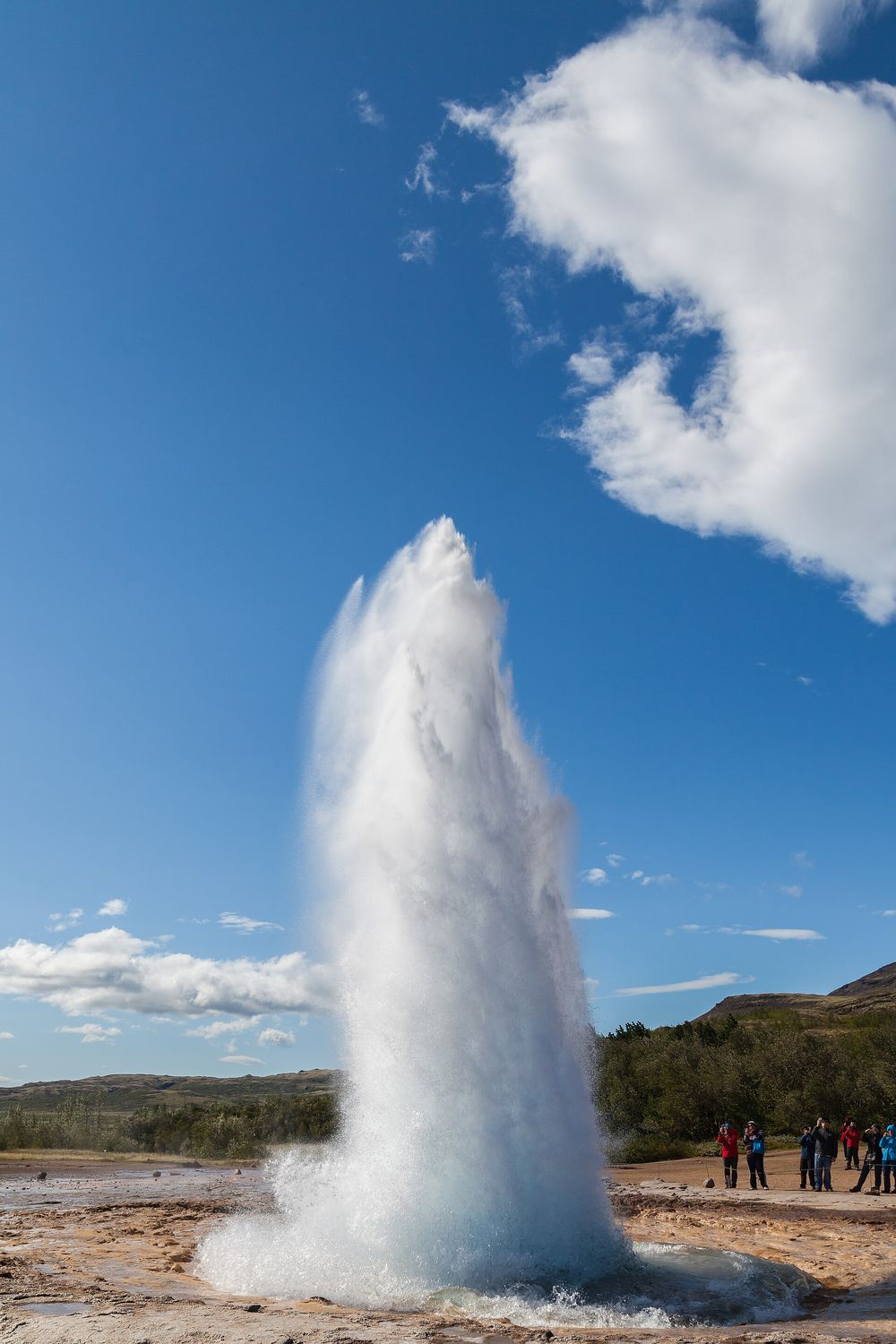 Strokkur geyser hurling boiling water high into a blue sky